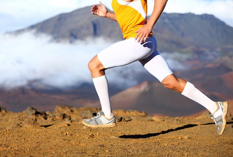 Ein Läufer joggt durch die Natur mit gesunden Beinen dank Kompression.