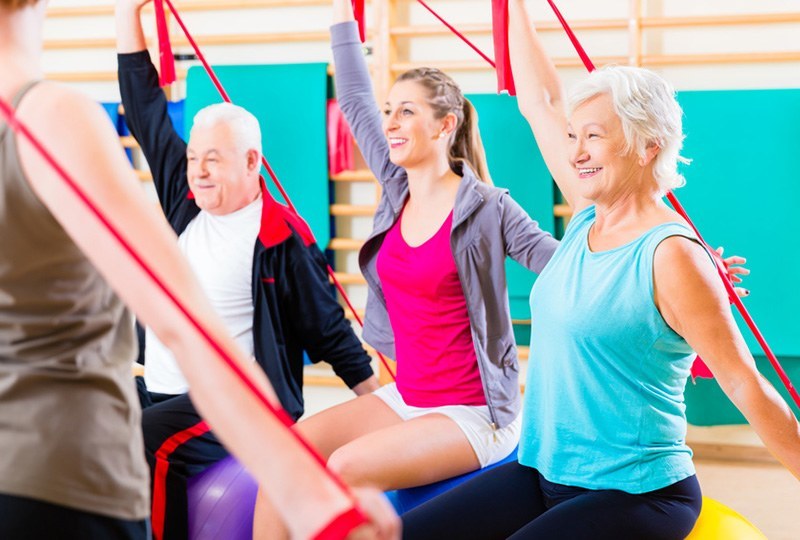 Eine Seniorengruppe zur Rehabilitation trainiert mit Therapiebändern für mehr Mobilität.